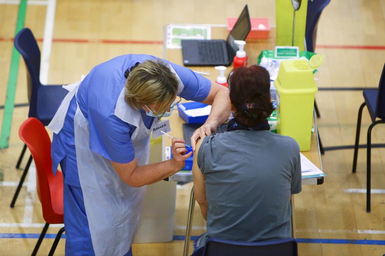 Mulher recebe aplicação de vacina da AstraZeneca contra Covid-19 no estádio de Cwmbran, em Gales do Sul, Reino Unido